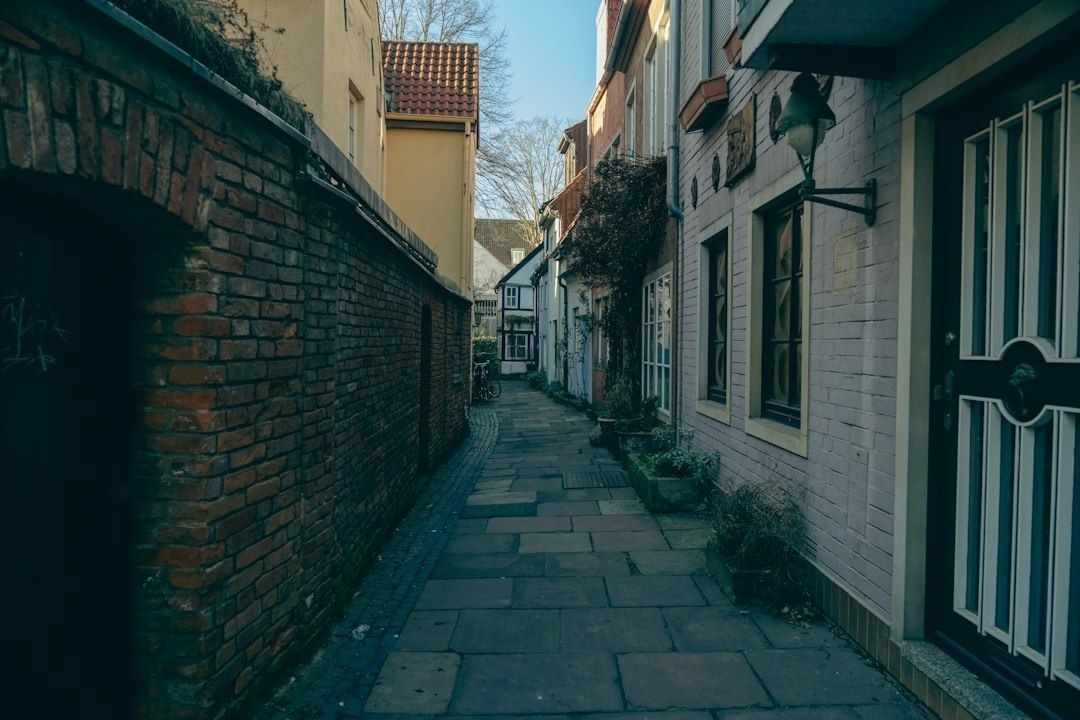 En stilla kullerstensgränd mellan äldre tegelhus i morgonljus